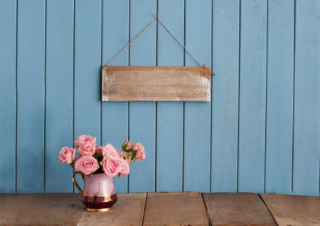 Beautiful pink roses in a vintage jug on rustic wooden backgroundの写真素材