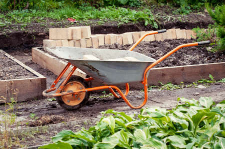 Wheelbarrow in a green rural garden on a summer day の写真素材