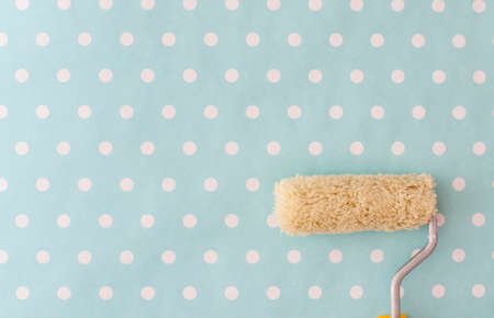 yellow paint roller over blue polka dot wallpaper in nursery roomの写真素材