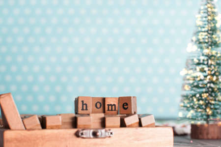 Wooden stamps with word HOME and christmas evergreen tree decorated with garland in nursery roomの写真素材