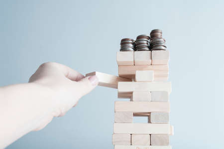 Human hand pulling wooden brick from the tower. Concept of planning, risk and strategy in business