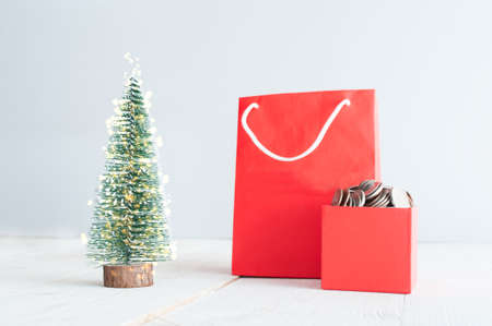 Red shopping bag and gift box with coins on the christmas treeの写真素材