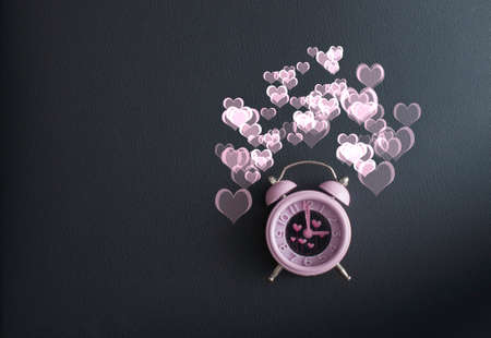 It's love o'clock. Valentine's pink alarm with heart shaped symbols on black leatherの写真素材
