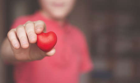 Boy holding red heart shape in his handの写真素材