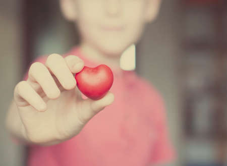 Boy holding red heart shape in his handの写真素材
