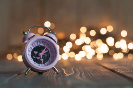 It's time for love. Valentine's pink alarm with heart shaped symbols on bokeh lightsの写真素材