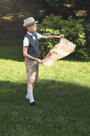 Little traveler in hat looking at old map