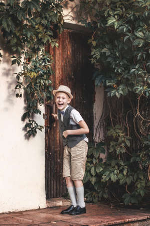 Boy in hat laughing near the door in a countryside residenceの写真素材