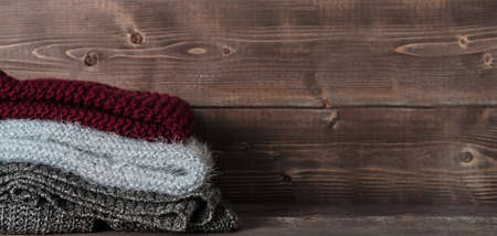 warm sweaters and scarf for cold weather on wooden shelf in the closet