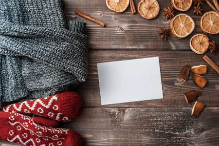 Rustic winter flatlay with cozy home sweater, mittens, blank greeting card and spices for mulled wine: anise; cinnamon and dried orangesの写真素材