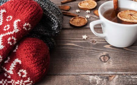 Rustic winter flatlay with cozy home sweater, mittens, cup of black tea and spices for mulled wine: anise; cinnamon and dried orangesの写真素材