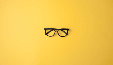 Black glasses frame on a bright yellow backgroundの写真素材