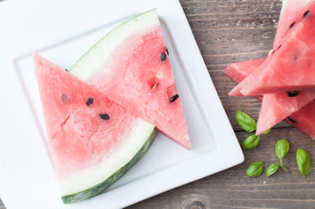 Summer juicy vegan healthy food. Vegetarian snack. Refreshing watermelon and basil leavesの写真素材