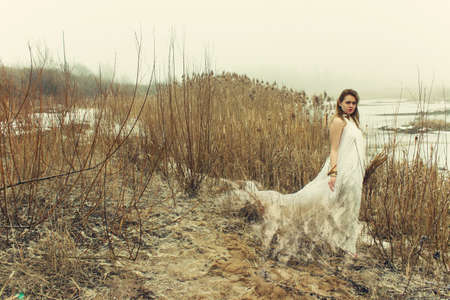 woman in white dress in the winter on the rushy lakeの写真素材