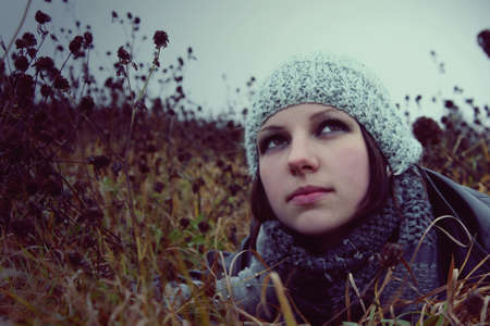 portrait of a girl lying in a meadow autumn in hat and gloves