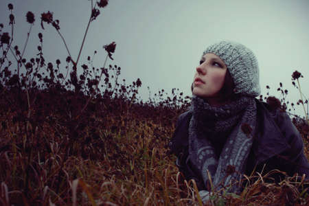 portrait of a girl lying in a meadow autumn in hat and gloves