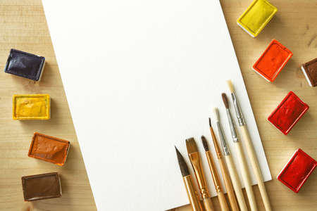 Blank piece of paper on table with brushes and paintの写真素材