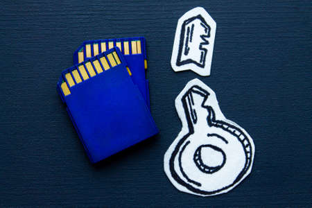 Blue SD memory cards and paper cut broken key on dark blue surface, concept of information security...