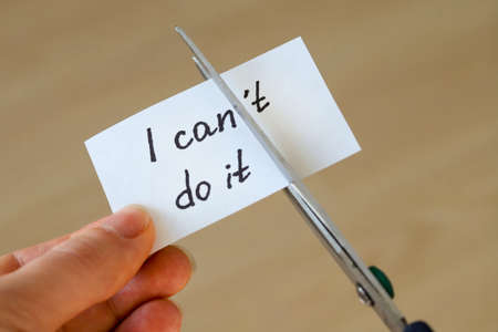 Scissors about to cut the piece of paper in half, turn inscription "I can't do it" on paper into "I can do it", motivation conceptの写真素材