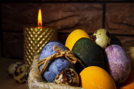 Colored Easter eggs and burning candle, dark backgroundの写真素材