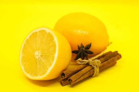 Sliced lemon and cinnamon sticks on yellow backgroundの写真素材