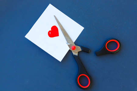 Piece of paper with painted heart and broken scissorsの写真素材