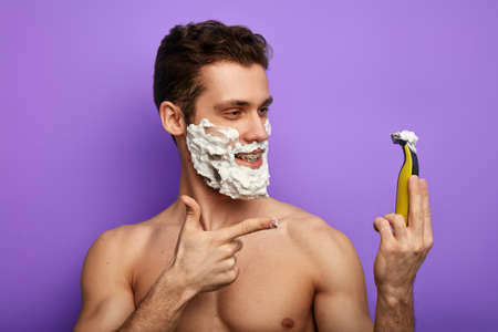 happy positive shirtless guy pointing at the shaver. close up photo.gel which will guarantee a great shaveの写真素材