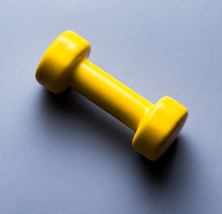 yellow dumbbell Isolated on blue background, top view photo.useful tool for fitness, crossfit.lifestyleの写真素材