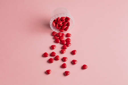 minimal concept . red little hearts with open glass bottle on pink background, top view photo. copy spaceの写真素材