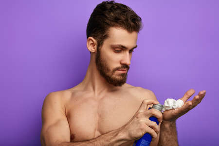young gorgeous bearded man cares of his face, beauty concept.close up photo. isolated blue backgroundの写真素材