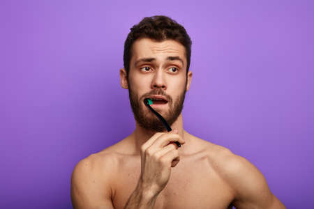 bearded young good looking guy has morning routine. Stomatology conceptの写真素材