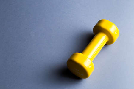 a yellow dumbbell lying on the blue table, copy space. top view photo, sporty life, health, body careの写真素材