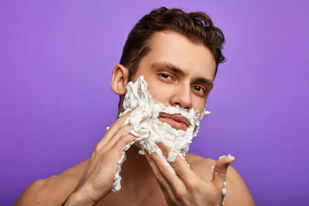 awesome man using cream in the blue background. close up photo.skin care concept