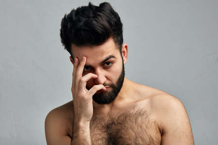 Handsome thoughtful shirtless man covering face with palm, feels bored and depressed, depression and sadness concept. offense. isolated gray background, what a shame. man is disappointed in somebodyの写真素材