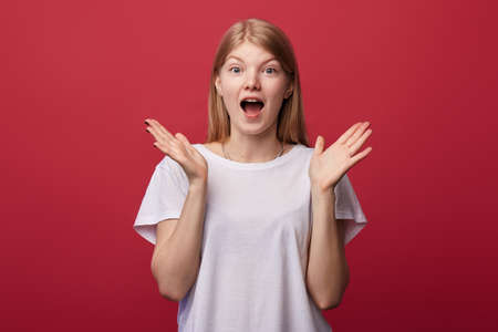 frightened emotional woman with opened mouth and raised hands, expresses her feeling, emotion. close up portrait. isolated red background, studio shot. sale, student is afraid of exaamsの写真素材
