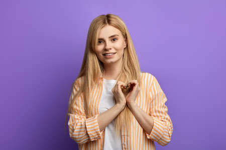 Smiling young awesome girl in striped shirt and white T-shirt showing heart with two hands, love sign. I love u. I miss you.emotion, feeling Smiling young awesome girl in striped shirt and white T-shirt showing heart with two hands, love sign. I love u. I miss you.emotion, feeling