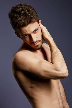 shirtless attractive serious man checking his face, skin care, man is going to shave his beard, close up photo. isolated black backgroundの写真素材