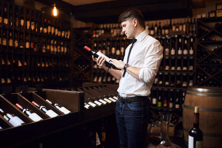 awesome man selling wine. wine trade, business concept. side view photo. wine expert with a bottle of wineの写真素材