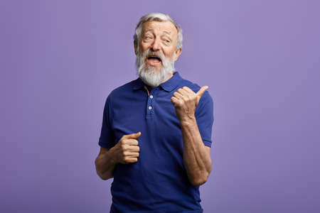 funny friendly kind man showing to the side. close up portrait. studio shot.