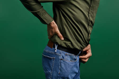 elderly man touching his back. acute symptom of osteoarthritis.c ose up cropped side view photo.