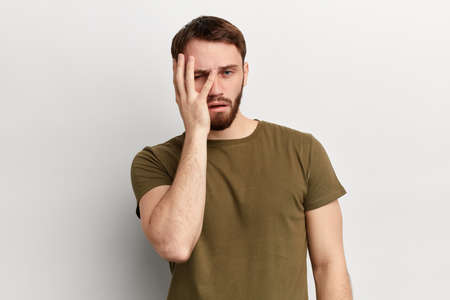 Young handsome dissapointed unhappy depressed tired man covering his eyes and face with palm, being...
