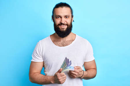 bearded businessman with money looking at the camera, prosperous business, man has won money in the lotteryの写真素材