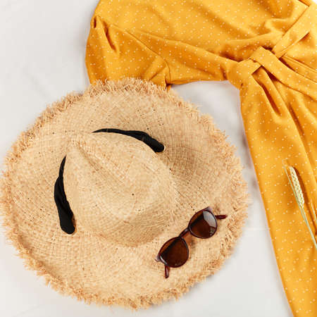 stylish straw female hat and light yellow dress for summer holiday. top view photo. shopping.