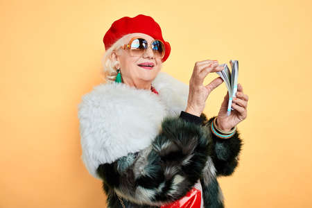 grandmother rejoicing at earned money, holiday, success, happiness concept. isolated yellow background.の写真素材