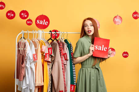 pleasant lovely girl advertising sale in the mall, close up photo. isolated yellow backgroundの写真素材