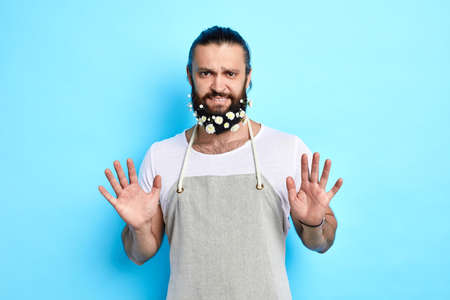 Attractive handsome man shows refusal gesture, angry expression, poses against blue background, body language.stopの写真素材