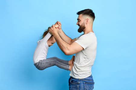 happy awesome dad doing exercises with daughter. close up side view photo. isolated blue background. studio shot. sport, healthy lifestyle. hobby, free time. spare timeの写真素材