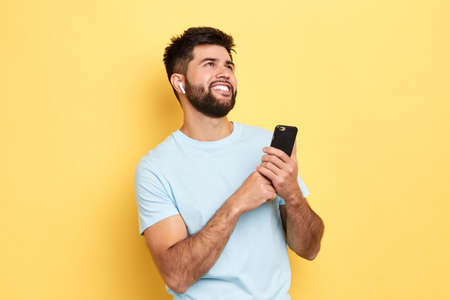 young attractive man holding smart phone and listerning to the radio. close up side view photo...