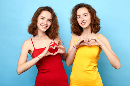 Beautiful young women showing heart symbols Romantic concept.close up phot. studio shot, feeling and emotion.sisters love each other.の写真素材