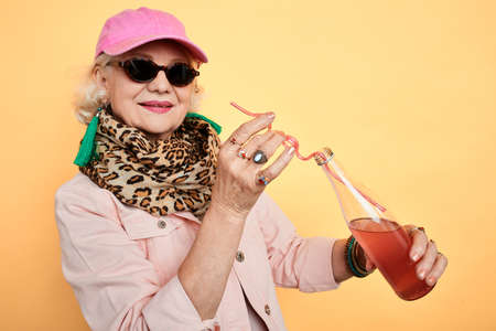 charming smiling stylish woman in pink cap and fashion casual clothes enjoying exotic drink. close...